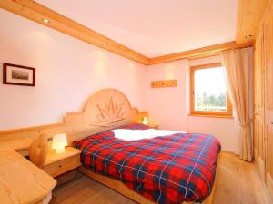 a bedroom with a bed with a plaid blanket at Apartment Chesa Sül Muot by Interhome in St. Moritz