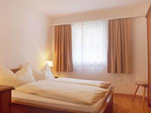 a bedroom with a white bed with a window at Apartment Chesa Sur Val 22 by Interhome in St. Moritz