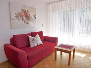 um sofá vermelho numa sala de estar com uma mesa em Apartment Haus Sacherer by Interhome em Bischoffingen