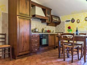 Fattoria SpedalettoにあるApartment Casanuova - Vecchia Cucina - LAI132 by Interhomeのキッチン(木製キャビネット、テーブル、椅子付)