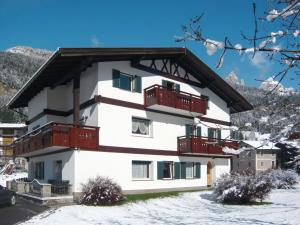 a white building with red balconies in the snow at Apartment Cincelli - Catinaccio by Interhome in Pozza di Fassa