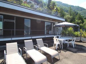 een patio met witte stoelen en tafels en een parasol bij Apartment La Cava-7 by Interhome in Pognana Lario