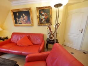 ein Wohnzimmer mit roten Ledermöbeln und Gemälden in der Unterkunft Apartment Sonnenkamp-4 by Interhome in Groß Zicker