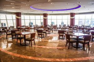 Beau Site Belle Vue Hotel في مرسى مطروح: مطعم بطاولات وكراسي في غرفة بها نوافذ