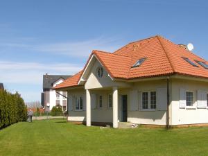 a house with an orange roof on a green yard at Holiday Home Mały dworek by Interhome in Łeba
