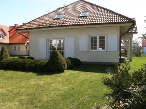 a small white house with a grass yard at Holiday Home Mały dworek by Interhome in Łeba