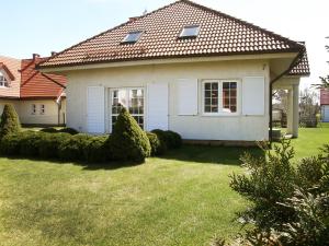 una pequeña casa blanca con un patio de césped en Holiday Home Mały dworek by Interhome, en Łeba