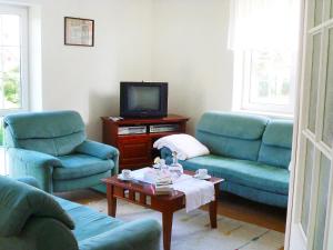 a living room with two blue chairs and a tv at Holiday Home Mały dworek by Interhome in Łeba