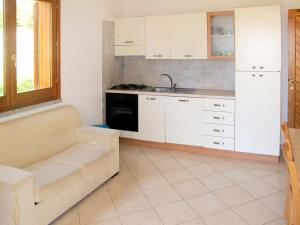 モンテ・ナイにあるHoliday Home Case Greche - REI234 by Interhomeの白いキャビネット、シンク、ソファ付きのキッチンが備わります。