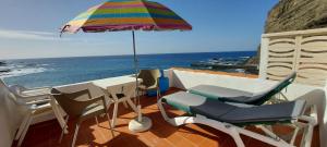 a balcony with a table and chairs and an umbrella at Vv Puesta de Sol in Alojera