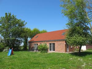 une maison en briques avec un toit rouge dans un champ dans l'établissement Holiday Home Altes Schöpfwerk-4 by Interhome, à Bunde