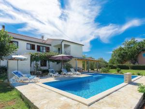 uma piscina com cadeiras e guarda-sóis em frente a uma casa em Holiday Home Ana Lucija - RCA508 by Interhome em Pula