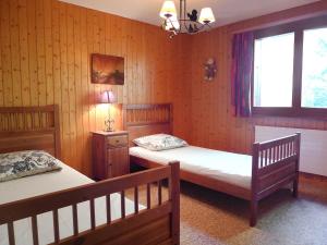 two beds in a room with wood paneled walls at Apartment Parc B 431 by Interhome in Champex