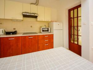 eine Küche mit Holzschränken und einem weißen Kühlschrank in der Unterkunft Apartment Pusa by Interhome in Sveti Filip i Jakov