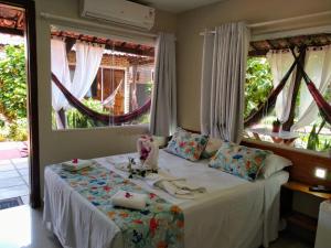 a bedroom with a bed and two large windows at Pousada Mar Mai in Pipa