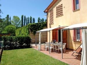 um pátio com uma mesa e cadeiras sob guarda-sóis em Villa Il Cipresso by Interhome em Marti