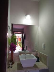 a bathroom with a sink and a large mirror at Pousada Mar Mai in Pipa