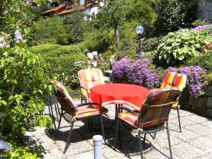 einen Tisch und drei Stühle mit einem roten Tisch und Stühlen in der Unterkunft Apartment Maier-1 by Interhome in Triberg