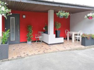 a red wall with a patio with a table and chairs at Apartment Nürburgblick by Interhome in Quiddelbach