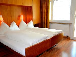 duże łóżko z białą pościelą i drewnianym zagłówkiem w obiekcie Apartment Chesa Ova Cotschna 306 by Interhome w Sankt Moritz