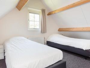 ウェーメルディンゲにあるHoliday Home Zeeuwse Cottage Wemeldinge-5 by Interhomeの白い壁の客室で、ベッド2台、窓が備わります。