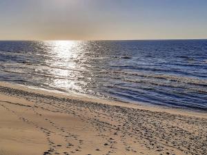 plaża z odciskami stóp w piasku i oceanie w obiekcie Holiday Home Zakątek Ventus II by Interhome w Smołdzińskim Lesie