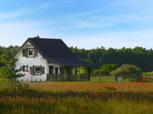 a white house with a black roof in a field at Holiday Home Zakątek Ventus II by Interhome in Smołdziński Las