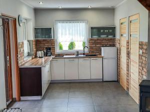 a large kitchen with white cabinets and a window at Holiday Home Zakątek Ventus II by Interhome in Smołdziński Las