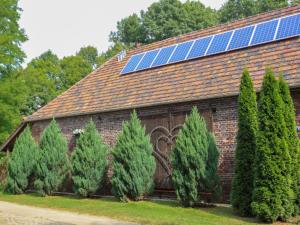 a barn with a group of pine trees and solar panels at Holiday Home Gościniec Pod Dwoma Sercami by Interhome in Tuplice