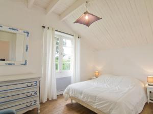 ein weißes Schlafzimmer mit einem Bett und einem Fenster in der Unterkunft Holiday Home Kerbourgnec in Saint-Pierre-Quiberon