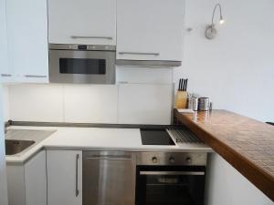 une cuisine avec des armoires blanches et des appareils en acier inoxydable dans l'établissement Apartment Les Cascadelles-5 by Interhome, à La Foux