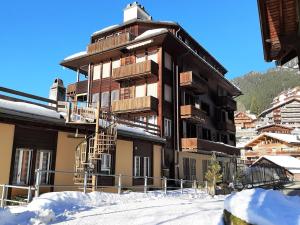 a large building with wooden balconies in the snow at Apartment Schweizerhof-1 by Interhome in Wengen