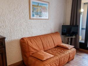 a brown couch in a living room with a tv at Apartment Les Cascadelles-2 by Interhome in La Foux