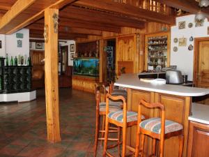 una cocina con armarios de madera y un bar con taburetes en Holiday Home Borówna by Interhome, en Lipnica Górna