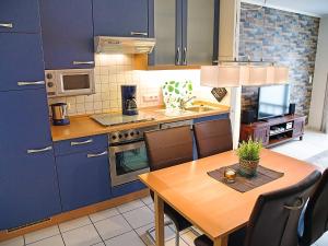 ノルトダイヒにあるApartment Witthuus-Baltrum by Interhomeのキッチン(青いキャビネット、木製テーブル付)