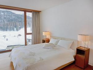 a bedroom with a white bed and a large window at Apartment Residenz Cresta Kulm B26 by Interhome in Celerina