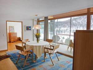 una sala da pranzo con tavolo, sedie e una grande finestra di Apartment Residenz Cresta Kulm B26 by Interhome a Celerina
