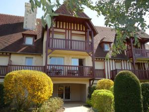 a large house with a balcony and bushes at Apartment Domaine de Clairefontaine-1 by Interhome in Deauville
