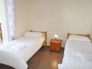 two beds in a room with a lamp on a night stand at Apartment Domaine de Clairefontaine-1 by Interhome in Deauville