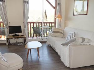 a living room with a white couch and a television at Apartment Domaine de Clairefontaine-1 by Interhome in Deauville