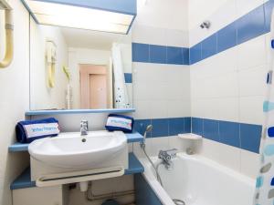 a blue and white bathroom with a sink and a tub at Apartment Les Marines-29 by Interhome in La Foux