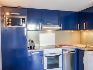 een keuken met blauwe kasten en een witte kookplaat bij Holiday Home Les Jardins de l'Océan-38 by Interhome in Pontaillac