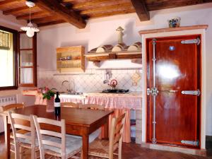 a kitchen with a wooden table and a wooden door at Apartment Podere La Torre-2 by Interhome in Certaldo