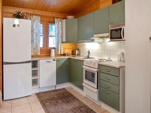 a kitchen with green cabinets and a white refrigerator at Holiday Home Kurre by Interhome in Lahdenperä +13 photos