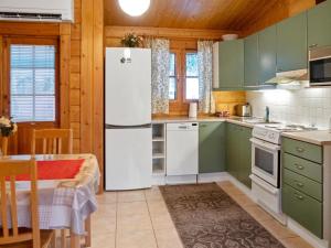 a kitchen with green cabinets and a white refrigerator at Holiday Home Kurre by Interhome in Lahdenperä
