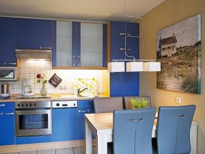 ノルトダイヒにあるApartment Witthuus-Spiekeroog by Interhomeのキッチン(青いキャビネット、木製テーブル付)