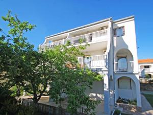 ein weißes Gebäude mit einem Balkon und einem Baum in der Unterkunft Apartment Fani-1 by Interhome in Rab