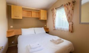 a bedroom with a white bed with two towels on it at Newby Bridge Country Caravan Park in Newby Bridge