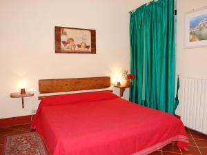a bedroom with a red bed and green curtains at Apartment Podere La Torre-1 by Interhome in Certaldo