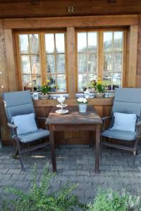 um pátio com 2 cadeiras e uma mesa de madeira em Apartment Bühlmann em Spiez